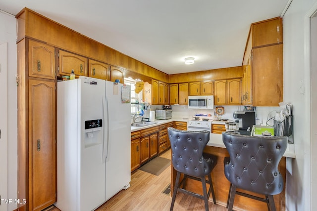 kitchen featuring light countertops, a sink, white appliances, a peninsula, and brown cabinetry