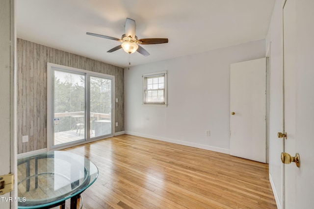 spare room with light wood-style floors, a ceiling fan, and baseboards