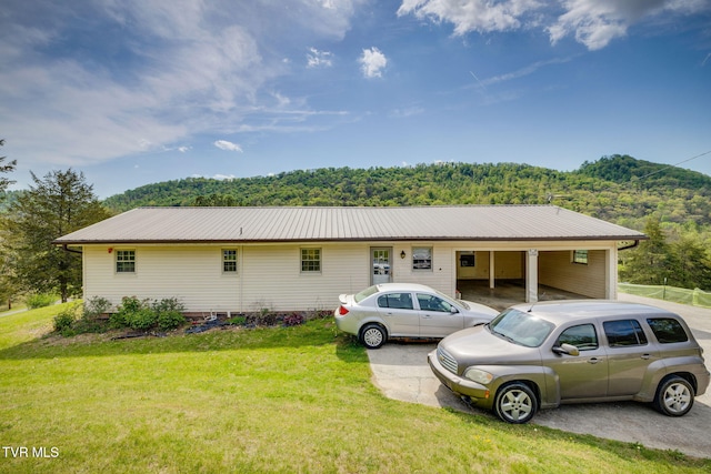 view of front of home featuring a view of trees, a front lawn, and metal roof