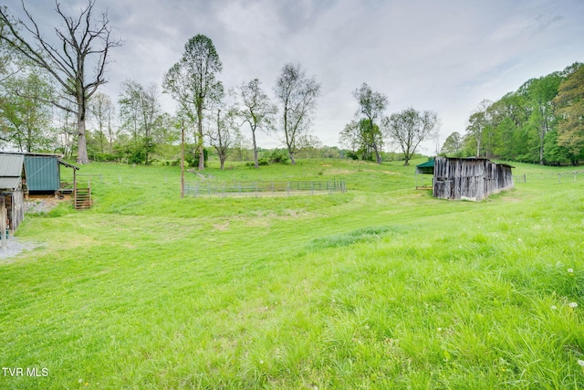 view of yard with an outdoor structure, an outbuilding, and a rural view