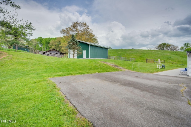 view of yard with a rural view, fence, and an outbuilding