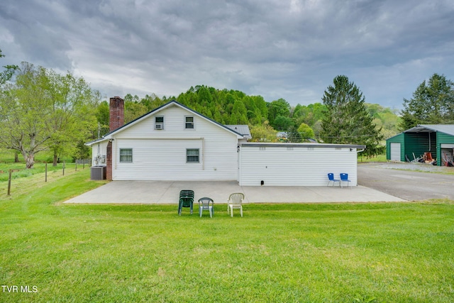 back of house featuring fence, cooling unit, a patio, a chimney, and a yard