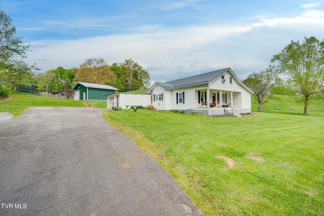 view of front of home featuring a detached garage, fence, a porch, and a front lawn