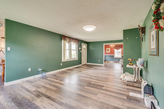 interior space featuring baseboards, a textured ceiling, and wood finished floors