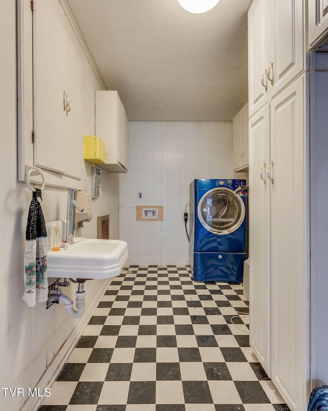 laundry room with washer / dryer, a textured ceiling, dark floors, a sink, and cabinet space