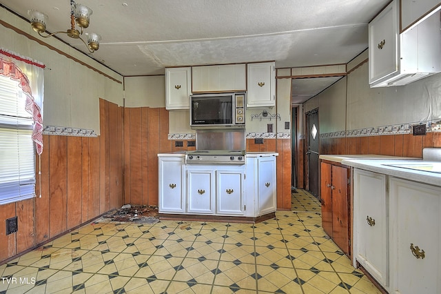 4418 Weaver Pike, Bluff City, TN 37618 - kitchen featuring stainless steel microwave, white cabinetry, wood walls, light floors, and light countertops