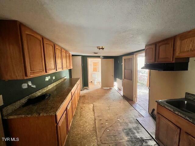 kitchen featuring dark countertops, brown cabinetry, a textured ceiling, and a sink