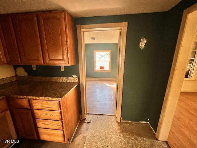 kitchen featuring dark countertops, brown cabinetry, and baseboards
