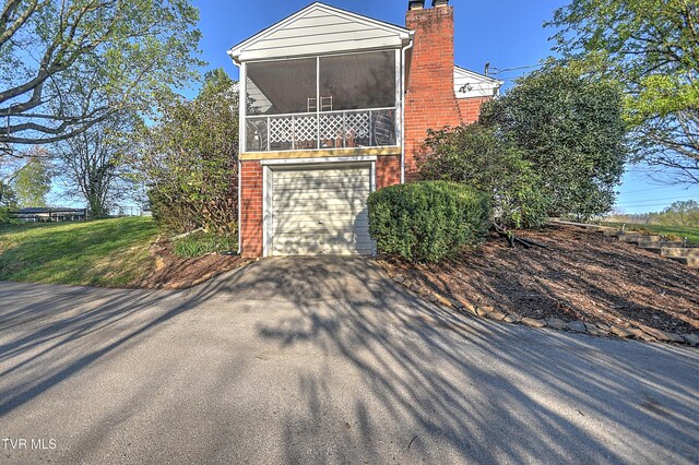 344 Virginia Dr, Bristol, VA 24201 - view of home's exterior featuring a chimney, driveway, brick siding, a sunroom, and a garage