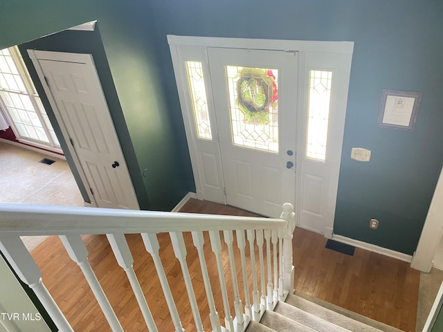 foyer featuring wood finished floors, stairs, baseboards, and visible vents
