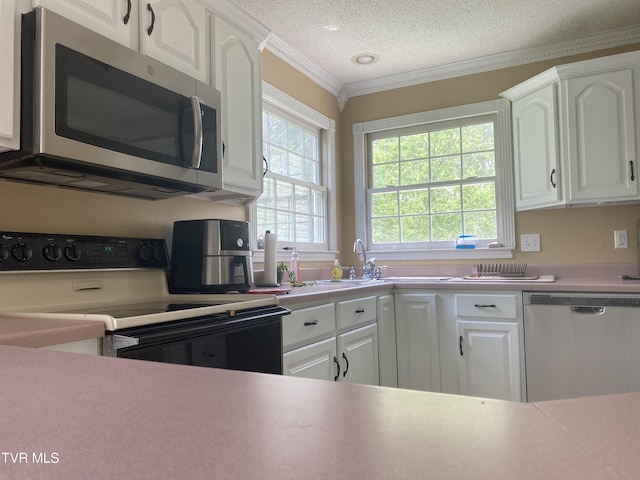 kitchen featuring crown molding, a textured ceiling, stainless steel appliances, light countertops, and white cabinetry