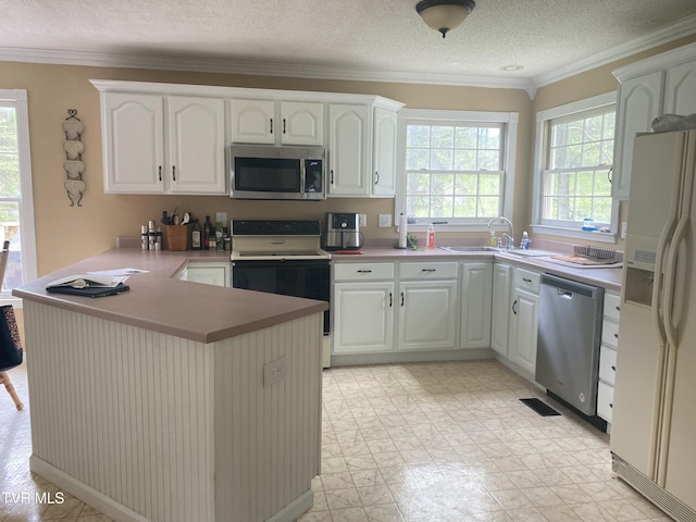 kitchen with stainless steel appliances, ornamental molding, a sink, a peninsula, and a textured ceiling