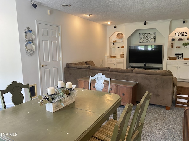 carpeted dining room featuring a textured ceiling and visible vents