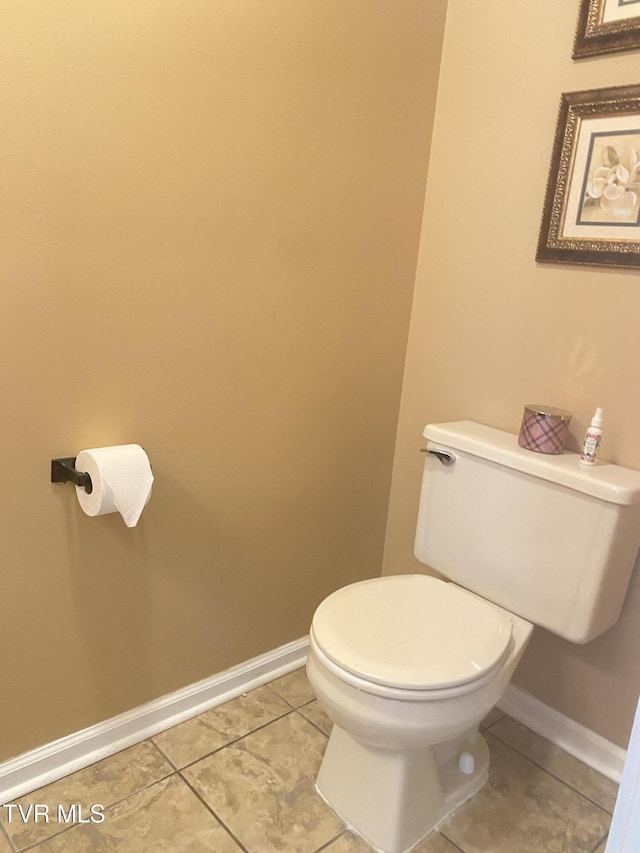 bathroom featuring tile patterned flooring, baseboards, and toilet
