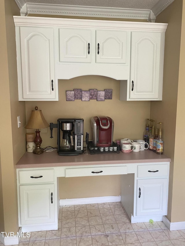bar with marble finish floor, baseboards, ornamental molding, and built in desk