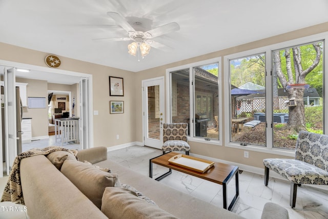 living room featuring a healthy amount of sunlight, marble finish floor, and baseboards