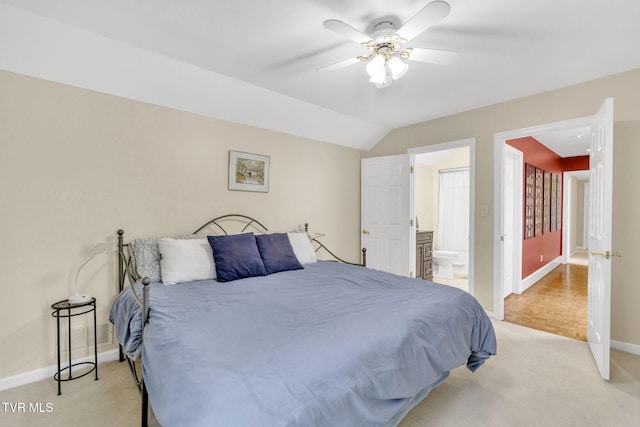 bedroom featuring vaulted ceiling, ensuite bath, baseboards, light colored carpet, and ceiling fan