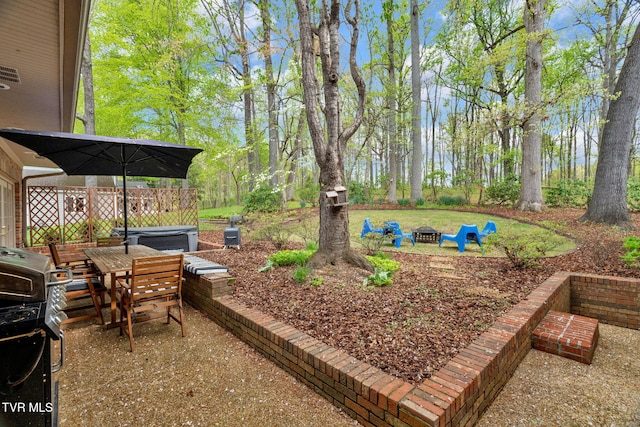 view of yard featuring a patio area, a fire pit, outdoor dining area, and a hot tub