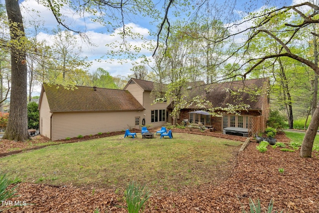 rear view of house featuring a fire pit, roof with shingles, a yard, and french doors
