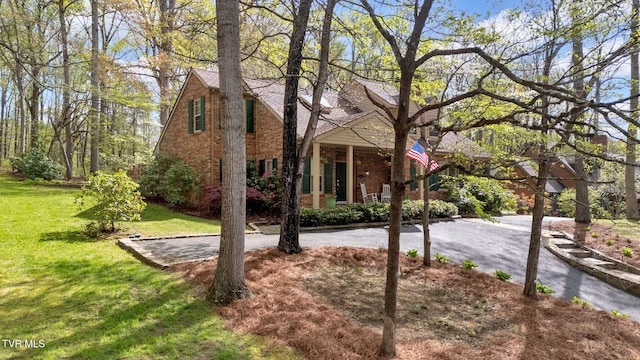 view of front of property featuring covered porch, a front lawn, and brick siding