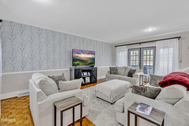 living room with crown molding, wallpapered walls, wainscoting, baseboards, and visible vents