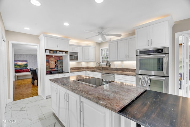 kitchen featuring white cabinets, a sink, a ceiling fan, marble finish floor, and appliances with stainless steel finishes