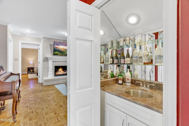 bar with indoor wet bar, a sink, ornamental molding, and a fireplace