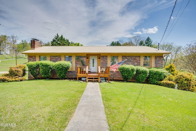 ranch-style home featuring a chimney, brick siding, and a front yard