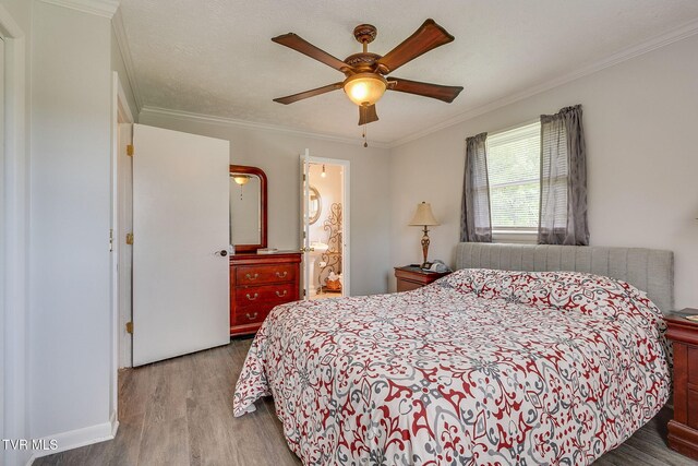 bedroom featuring wood finished floors, a ceiling fan, ornamental molding, and ensuite bathroom