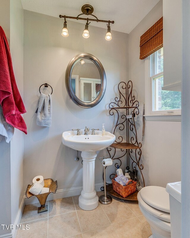 bathroom with tile patterned floors, baseboards, and toilet
