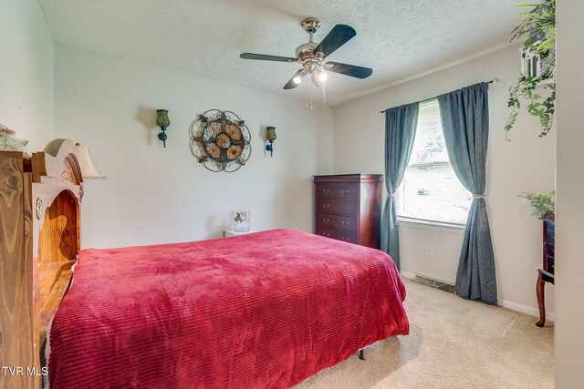 carpeted bedroom with a textured ceiling, baseboards, ceiling fan, and visible vents