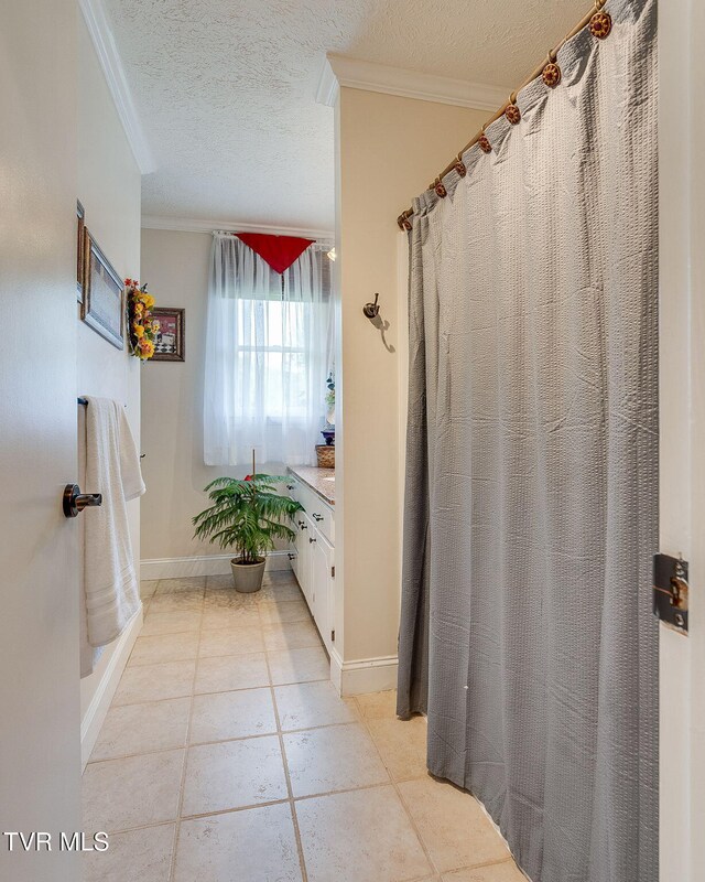 full bathroom with baseboards, crown molding, tile patterned flooring, and a textured ceiling