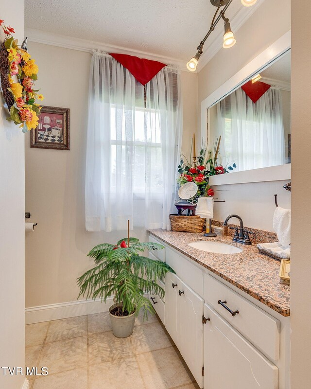 bathroom with baseboards, crown molding, vanity, and a textured ceiling