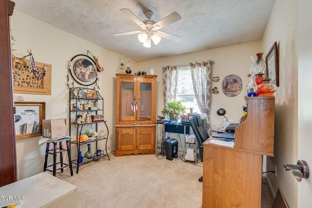 carpeted home office featuring a ceiling fan and a textured ceiling