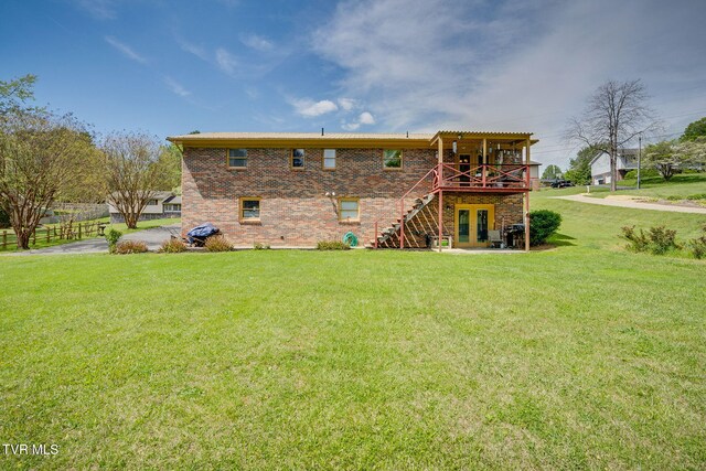 back of house featuring brick siding, a wooden deck, stairway, and a yard