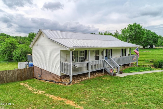 view of front of home featuring a front lawn, fence, crawl space, metal roof, and a porch