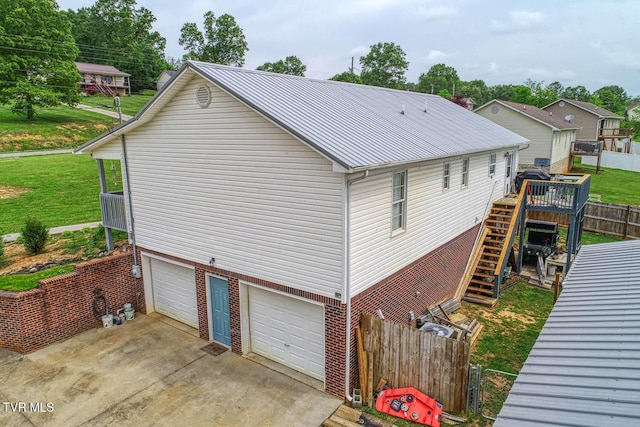 view of property exterior with metal roof, fence, a yard, an attached garage, and stairs