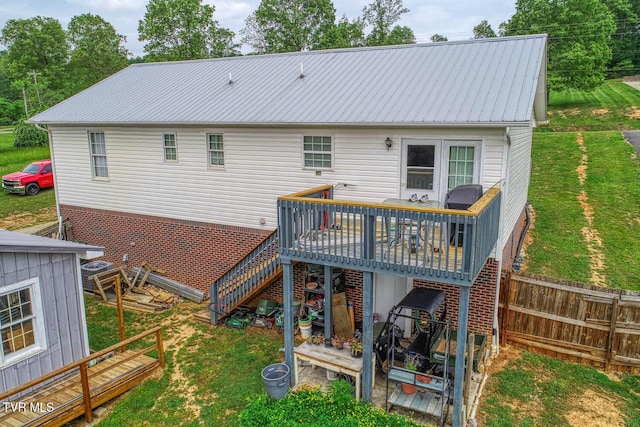 rear view of house with fence, stairs, a wooden deck, a lawn, and metal roof
