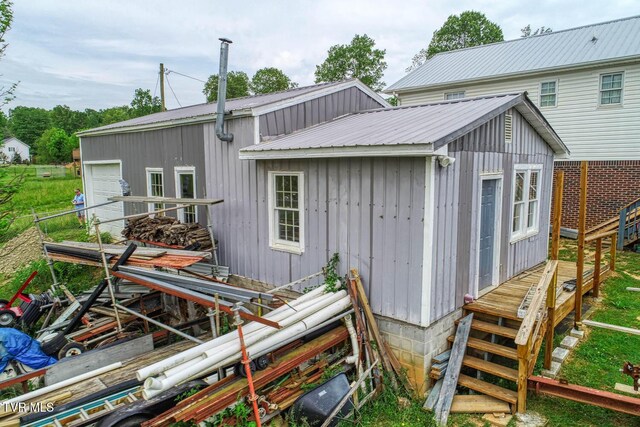 back of property with a detached garage, metal roof, and a wooden deck