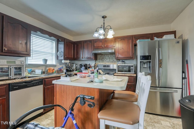 kitchen with a center island, light countertops, under cabinet range hood, and stainless steel appliances