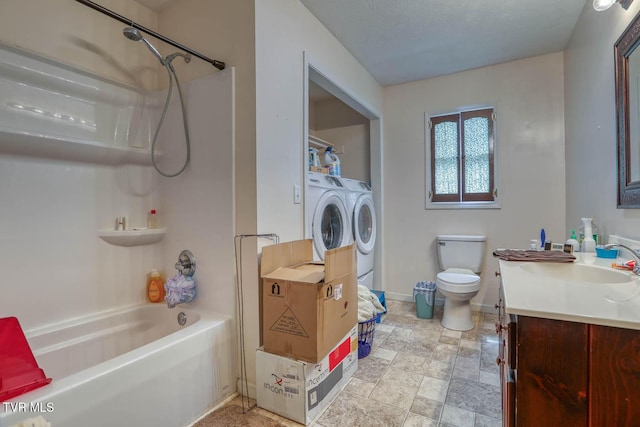 bathroom featuring bathtub / shower combination, baseboards, vanity, toilet, and separate washer and dryer