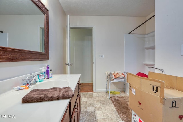 bathroom featuring vanity, baseboards, walk in shower, and stone finish floor