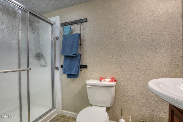 bathroom with a sink, a textured wall, toilet, and a shower stall
