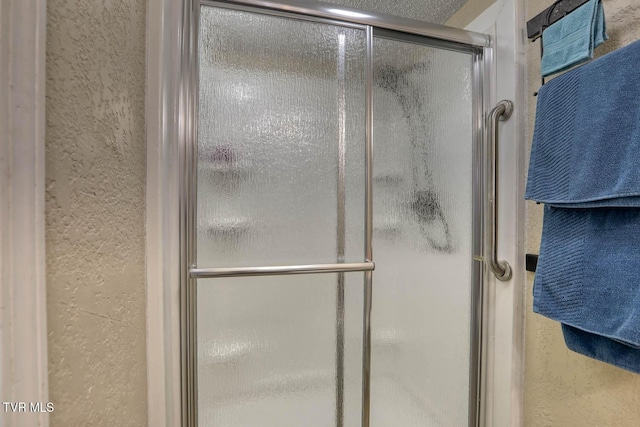 bathroom featuring a textured wall and a shower stall