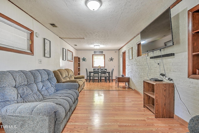 2856 Watauga Rd, Johnson City, TN 37601 - living area featuring light wood-style flooring, a textured ceiling, brick wall, and visible vents