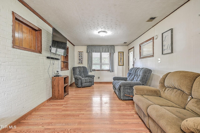 2856 Watauga Rd, Johnson City, TN 37601 - living room with a textured ceiling, light wood-type flooring, brick wall, baseboards, and visible vents