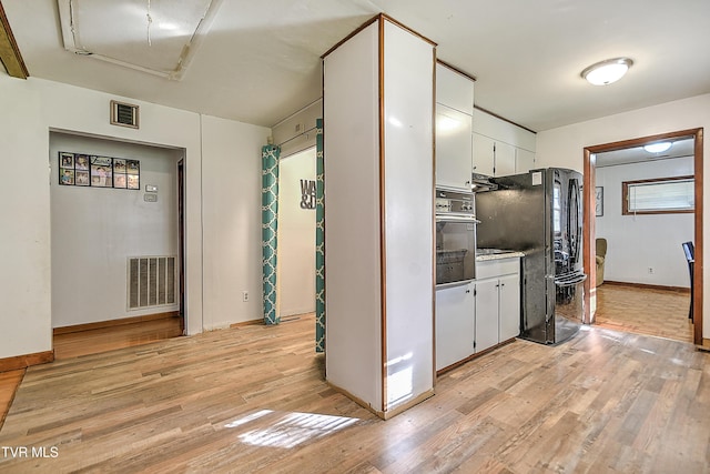 2856 Watauga Rd, Johnson City, TN 37601 - kitchen with stainless steel oven, white cabinets, visible vents, and light wood-style flooring