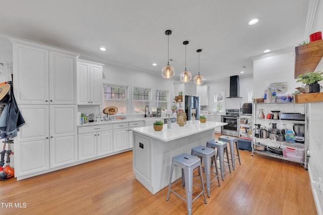 2040 Happy Valley Rd, Limestone, TN 37681 - kitchen with a breakfast bar area, appliances with stainless steel finishes, light countertops, white cabinets, and wall chimney exhaust hood