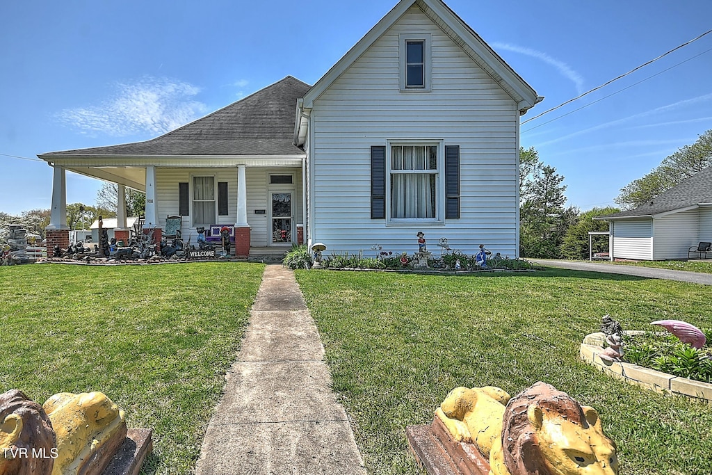 view of front facade featuring a front lawn, covered porch, and roof with shingles
