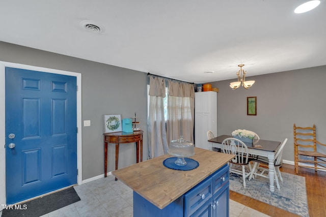 kitchen featuring visible vents, baseboards, blue cabinets, a notable chandelier, and decorative light fixtures